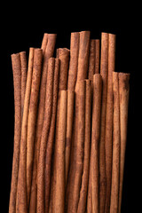 Cinnamon sticks arranged side by side, from above, isolated over black. Raw bark of Indonesian cinnamon, Cinnamomum burmannii, used as an aromatic condiment and flavouring additive in a wide variety.