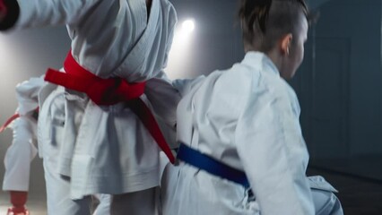 Focused kids training karate and practice fight technique. Males in white kimono sparring. Healthy kids. Smoky background with spotlights. Boys practicing karate. F4K, UHD