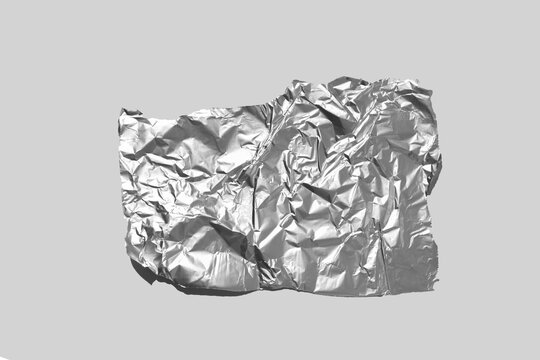 Shiny aluminum foil wrap without chocolate candy on a gray background. Texture of used crumpled aluminium food foil.