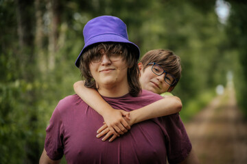 Two siblings in glasses share a happy moment, with the younger boy in a green t-shirt giving a...