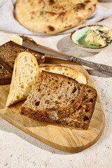 Rustic Bread Assortment on Cutting Board with Butter and Knife in Sunlit Summer Setting