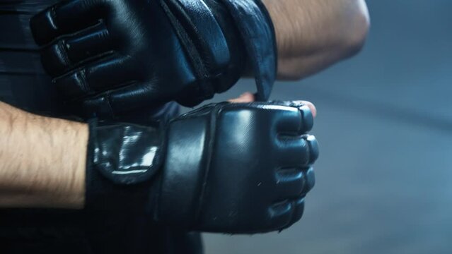 Man wearing boxing gloves before training in slow motion. Young athlete getting ready for fight. MMA fighter preparing. Sport concept in 4K, UHD