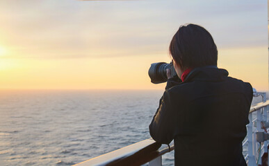 Female photographer taking photos on a cruise ship at sunset. Alaska. Alaska.
