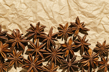 Anise stars background, top view close up macro photography fragrant spices dry anise seeds on crumpled baked paper, natural organic seasoning texture, food pattern, brown beige monochrome tone
