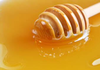 honey dripping from a wooden dipper