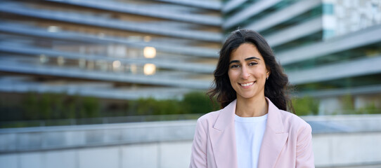 Headshot portrait of young middle eastern businesswoman standing at office building. Successful...