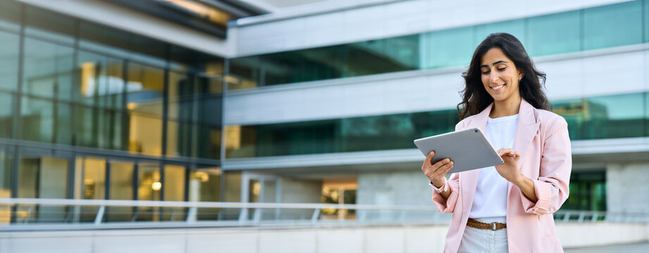 Banner of young middle eastern Israel businesswoman using tablet pc application for online remote work at office business building outdoors. Indian or arabic woman holding digital computer. Copy space