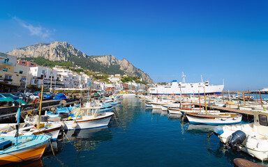 Obraz premium Welcome to Capri concept image. Morning view of Marina Grande in Capri, Italy, showcases serene turquoise waters, boats and picturesque coastal buildings under clear blue sky
