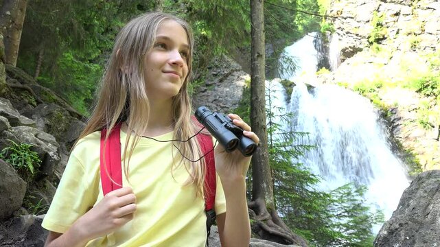 Girl Using Binoculars by Waterfall in Mountains, Child Hiking at Camping, Alpine Trails, Kid Traveling in Adventure Trip Vacation