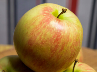 Ripe Apple Focus. A ripe apple with green and red hues on a surface, other apples blurred in the background, symbolizing freshness.