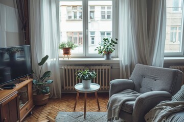 Fototapeta premium A cozy living room with a large window offering views of the city, potted plants, a comfortable armchair, and a television on a wooden cabinet