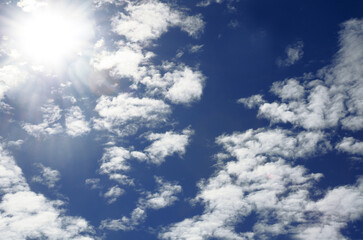 Bright light of the sun on a dark blue sky among the clouds.