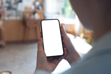 Mockup, woman's hands holding mobile phone with blank screen in coffee shop. Woman using...