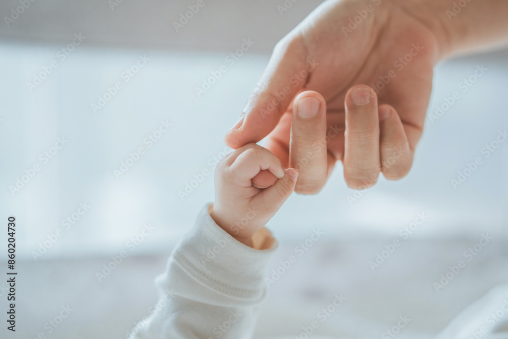 Wall mural close-up little hand of child baby holding hand of mother, a newborn holds on to mom's, dad's finger