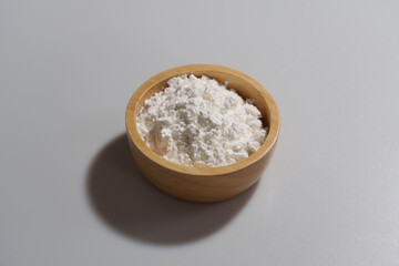 Close-up of corn starch or flour powder in wooden spoon on white background