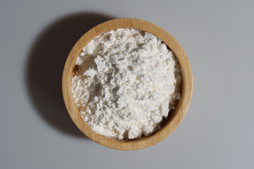 Close-up of corn starch or flour powder in wooden spoon on white background