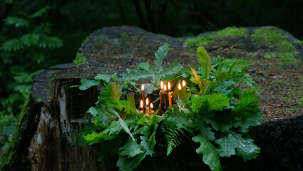 burning magic candles, oak and fern leaves on tree stump in forest, natural background. spiritual esoteric practice. Witchcraft. wiccan pagan Ritual. Summer Solstice Day, Midsummer, Ligo night, Litha