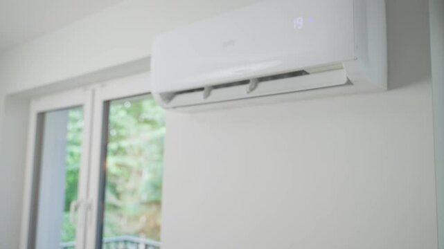 Hand adjusting temperature on air conditioner with remote control, Working air conditioner for comfort temperature in living room at hot summer