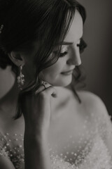 Naklejka premium A woman with long hair and a black dress is wearing a pearl earring. She is looking at the camera with a smile on her face