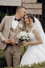 A bride and groom are posing for a picture, with the bride holding a bouquet of white flowers. The...