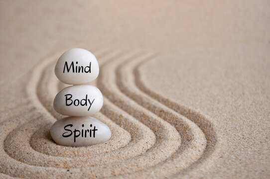 Mind, body and spirit text on Zen stones on sand background