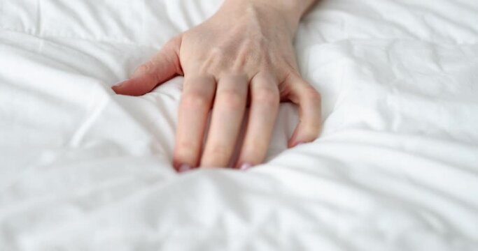 Woman hand squeezing white bed during passionate orgasm closeup 4k movie slow motion. Sexual pleasure concept