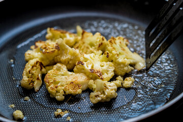 Chef at the kitchen preparing bean porridge with cauliflower and vegetables