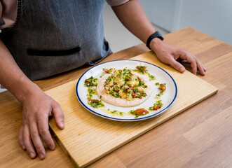 Chef at the kitchen preparing bean porridge with cauliflower and vegetables