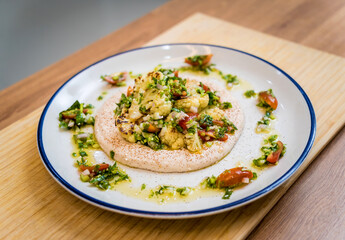Tasty bean porridge with cauliflower and vegetables on white plate