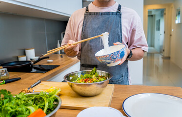 Chef at the kitchen preparing spicy glass noodle salad