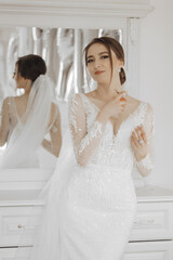 A woman in a white dress is standing in front of a mirror, applying perfume. Concept of elegance and sophistication, as the woman is dressed in a wedding gown