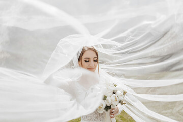 A bride is standing in front of a white veil, holding a bouquet of flowers. The scene is set in a field, with the bride's dress and veil creating a sense of elegance and romance