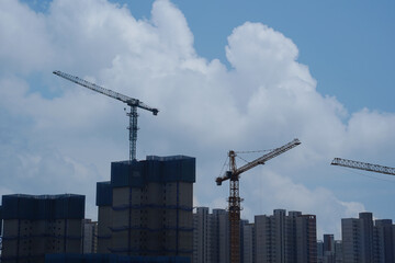 construction site with cranes and building under construction against blue sky