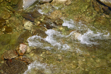 Water flows over the stones. Top view of a shallow river flowing along a rocky bottom.