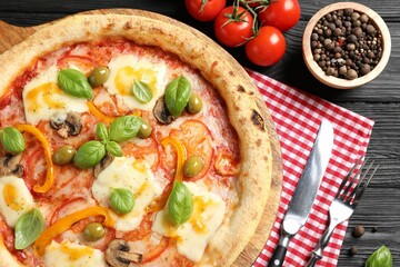 Delicious vegetarian pizza served on black wooden table, top view