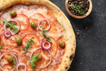 Delicious vegetarian pizza with arugula and peppercorns on black table, top view