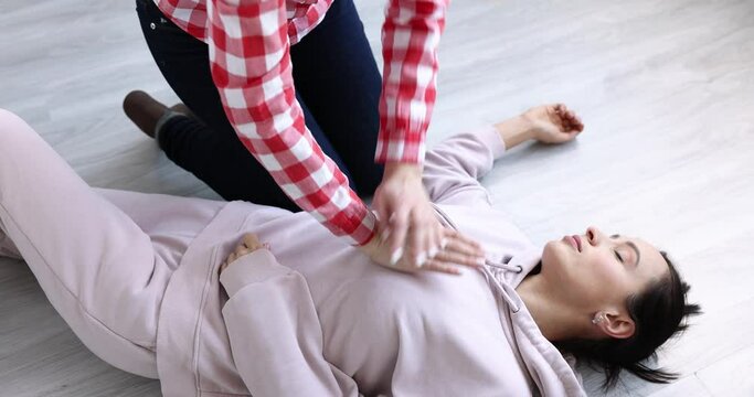 Woman looking at pulse on carotid artery and making indirect heart massage to unconscious man 4k movie. Cardiopulmonary resuscitation concept