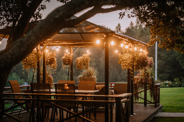 Blome, Latvia - September 11, 2023 - A cozy outdoor gazebo with hanging plants and string lights at...