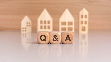 Cubes with message Q and A surrounded by wood home. Question and answer about housing problems