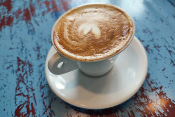 Fresh aro,matic cappuchino with heart foam on blue wooden table