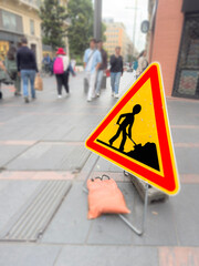Construction sign on pedestrian blurred people walking on street