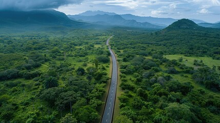 Fototapeta premium Aerial view of countryside asphalt road amidst green forest and mountains