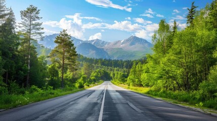 Scenic view of asphalt road leading through green forest and mountain backdrop