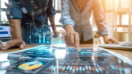 Two professionals analyzing data charts on a tablet and documents, planning business strategies with futuristic graphical overlays.