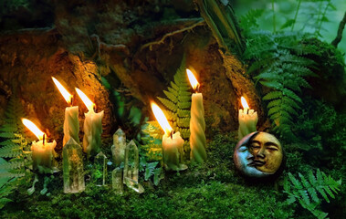 Burning candles, moon amulet and quartz crystals in forest, dark natural background. Wiccan...