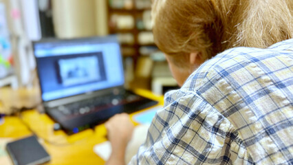 背中を丸めてノートパソコンを見る高齢女性