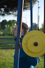 A dedicated young athlete puts in the hard work, vigorously training on gym equipment outdoors to...