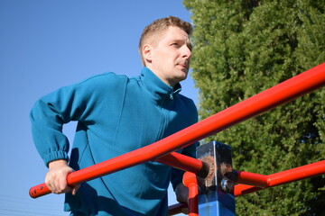 A dedicated young athlete puts in the hard work, vigorously training on gym equipment outdoors to...
