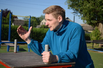 A dedicated young athlete puts in the hard work, vigorously training on gym equipment outdoors to...
