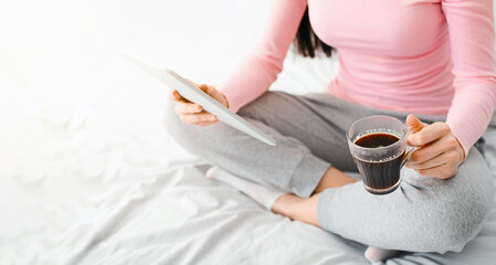 Cozy weekend at home. Millennial woman browsing on tablet and having coffee, empty space